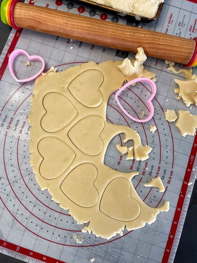a progress photo of dough being rolled and cookie cutters being used